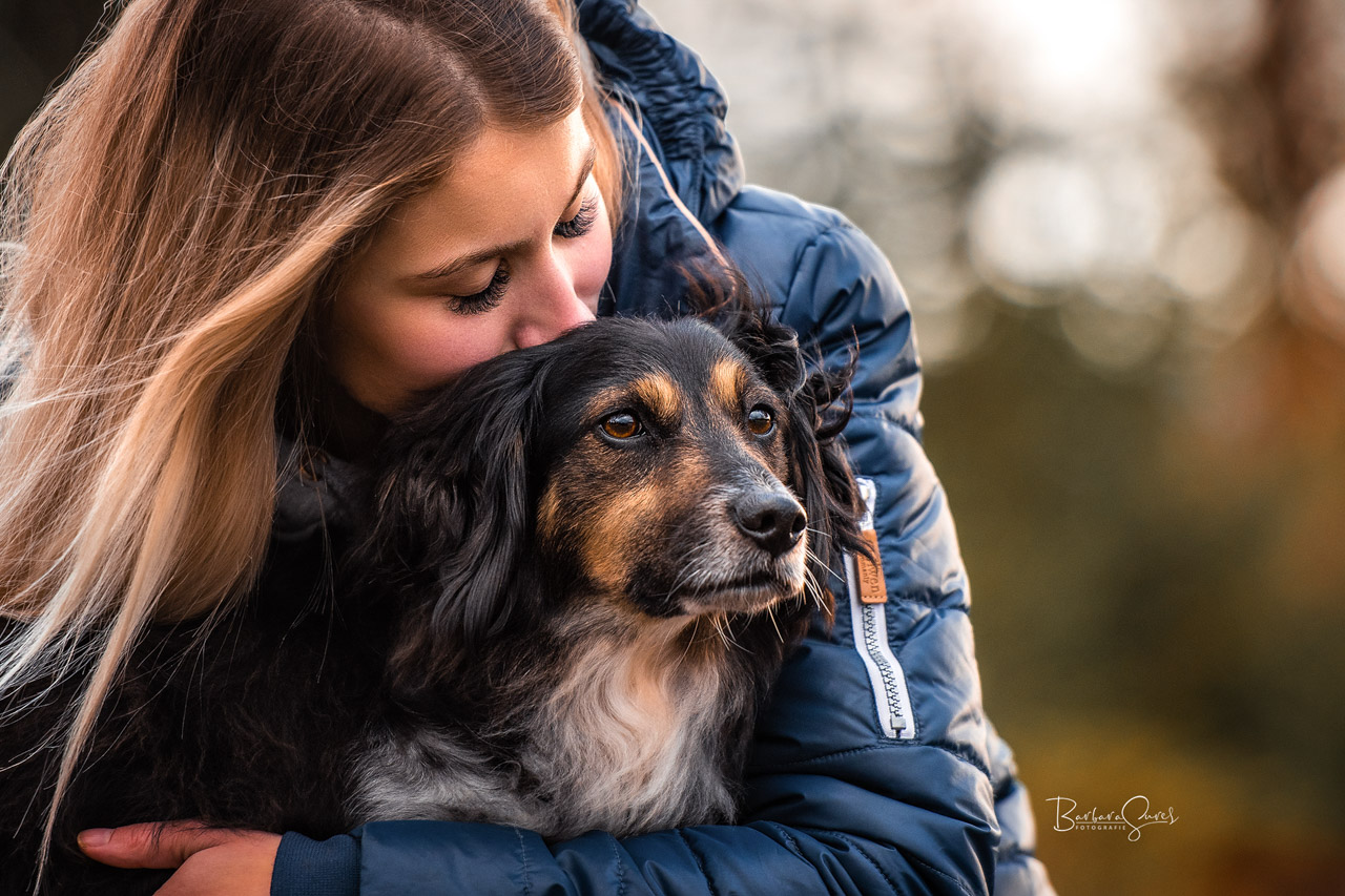 Eine junge Frau hält ihren Hund liebevoll im Arm
