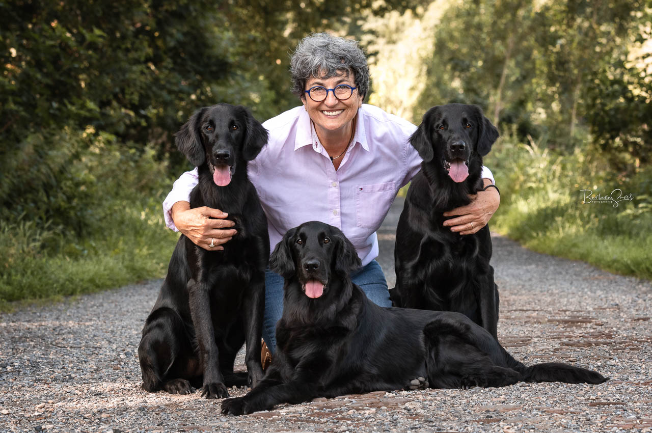 Frau sitzt mit ihren drei Hundenauf dem Boden