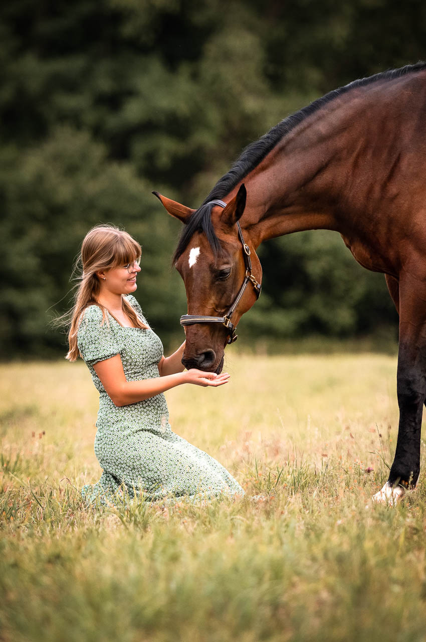 Junge Frau kniet vor ihrem Pferd
