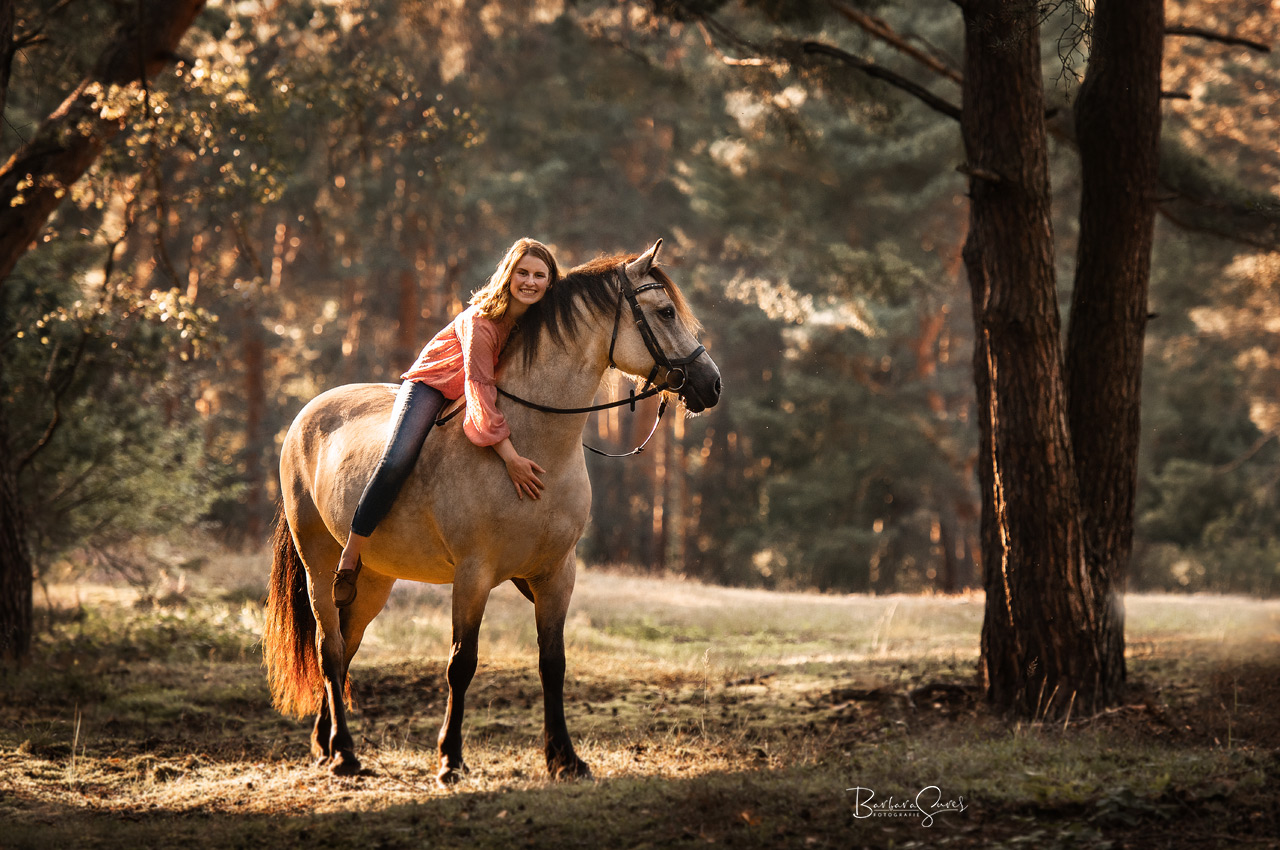 Eine junge Frau ist mit ihrem Pferd im Wald
